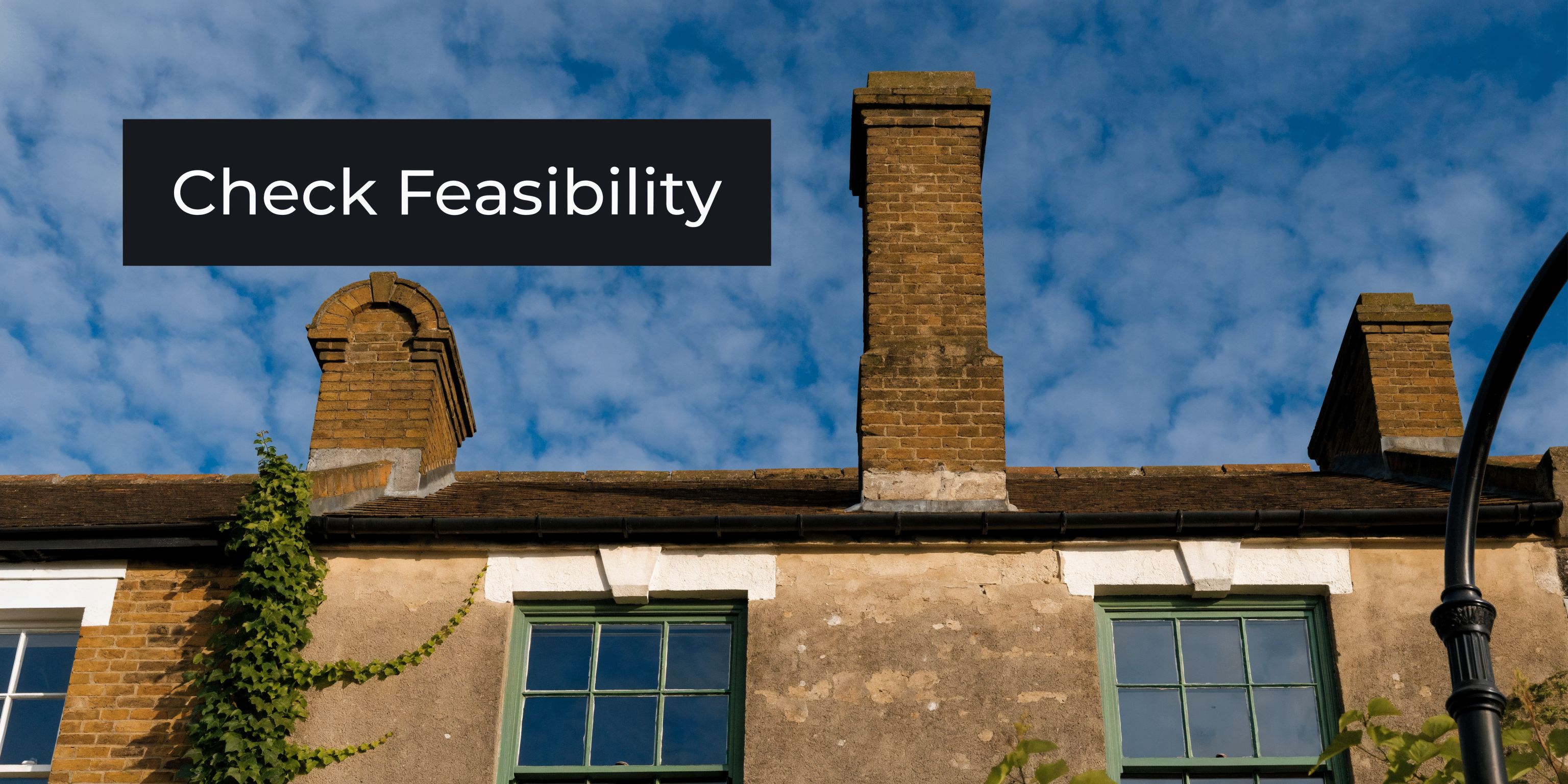 A close-up view of brick chimneys on the roof of a traditional terraced house against blue sky.