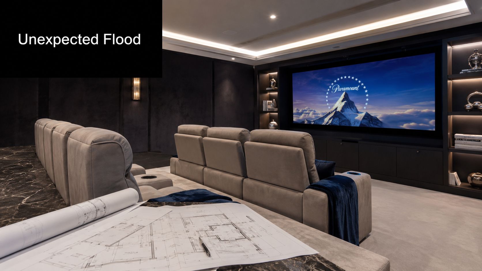 A modern private home cinema room featuring comfortable seating and architectural blueprints on a table.