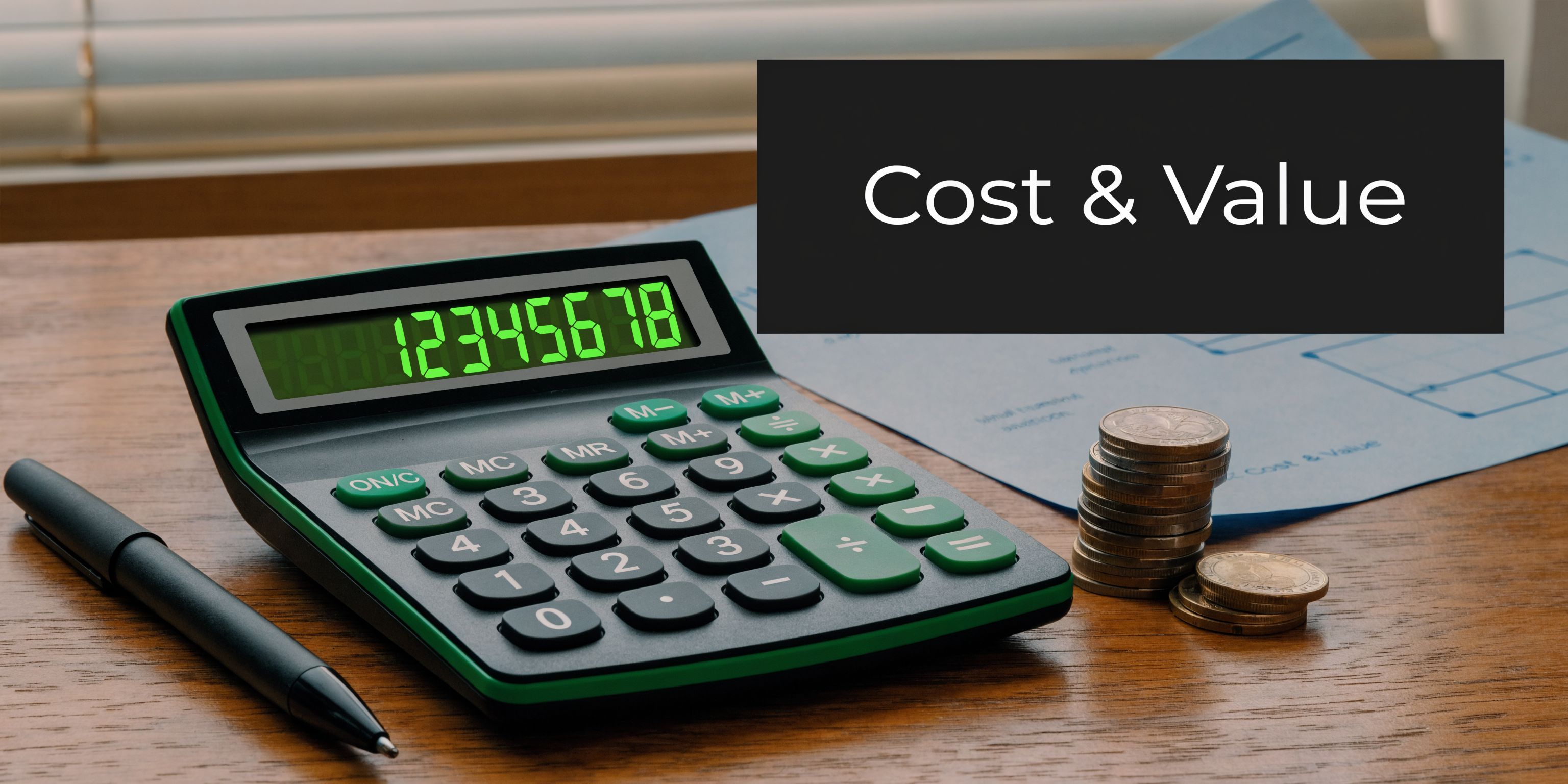 A black calculator, a pen, and a stack of coins resting on a wooden desk surface.