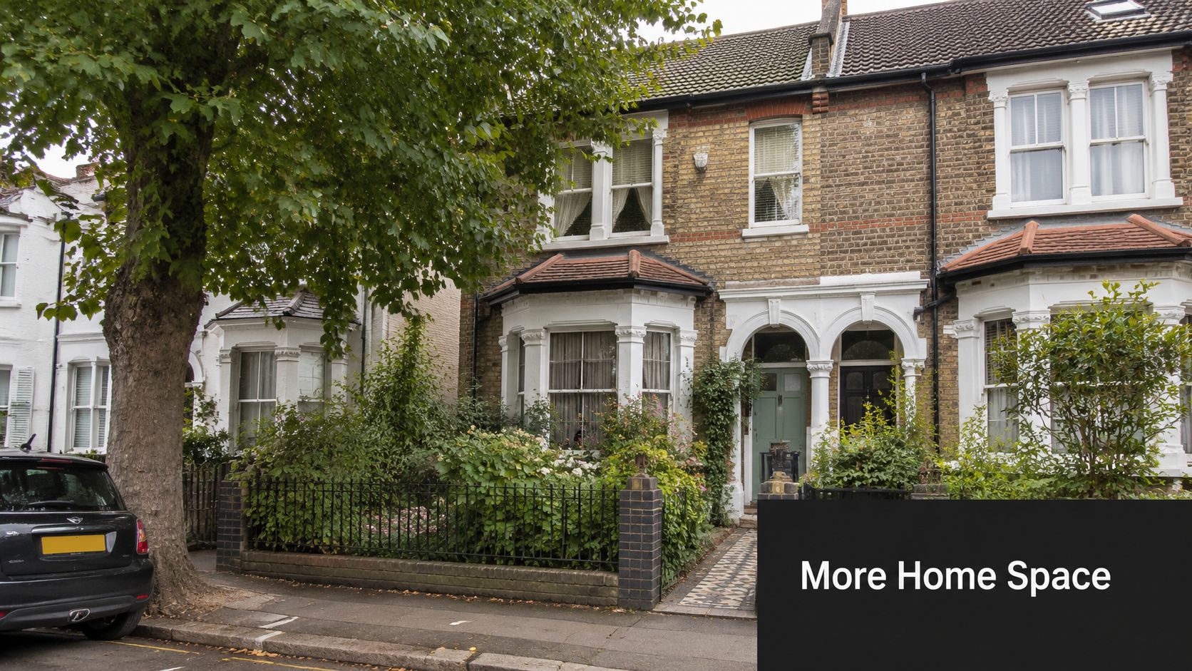A classic London residential street with traditional brick Victorian semi-detached houses featuring bay windows and green foliage.
