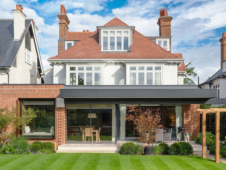 Brick and glazed rear extension beneath a white house with a red tiled roof