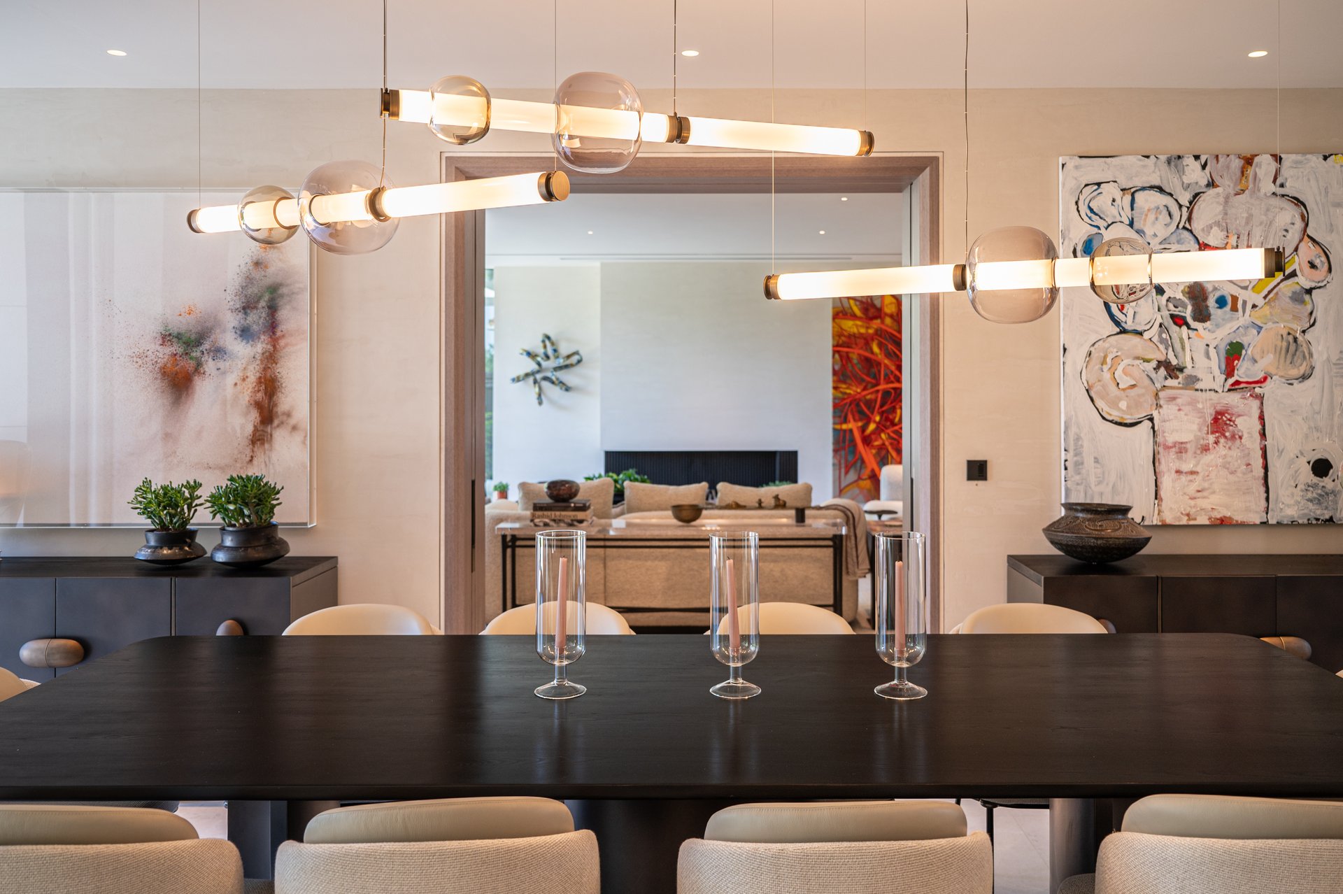 Dining and living space with sculptural pendant lighting and garden views